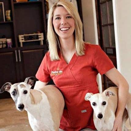 Dr. Bertrand smiling and holding two greynounds